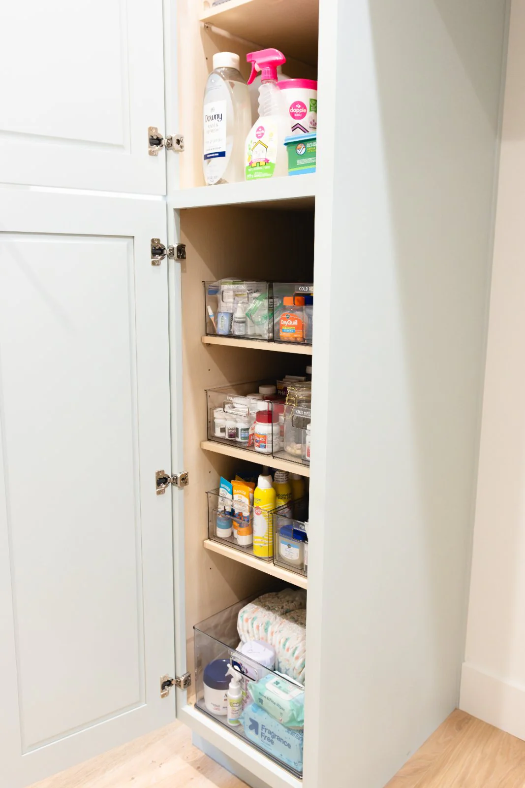 A laundry and household storage cabinet with labeled pull-out bins